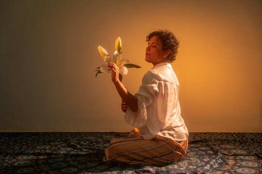 Spiritual Latin woman holding lily in warm golden light