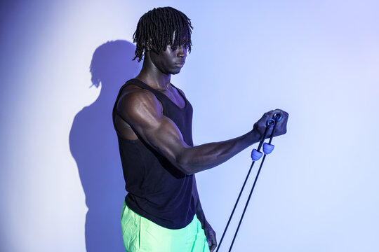 Black athlete training with resistance band in studio light