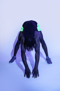 Black athlete stretching forward fold in studio lighting