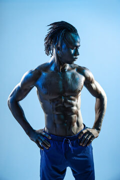 Muscular athlete posing in studio with blue lighting