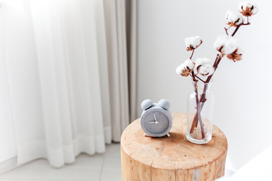 Alarm clock on bedside table. Home interior with cotton branch flowers and healthy sleep routine. Concept of biological clock, circadian rhythm, digital detox