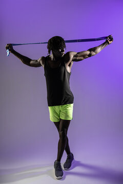 Black athlete stretching with resistance band in studio light
