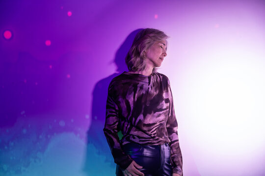 Futuristic senior Asian woman in purple neon light portrait