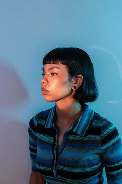 Young Latin woman in blue light portrait, side view