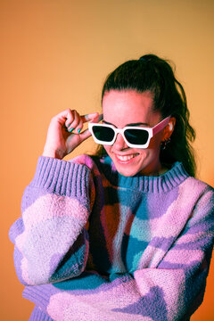Smiling woman in colorful sweater adjusting sunglasses