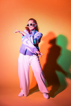 Stylish woman dancing in studio with colorful shadow light