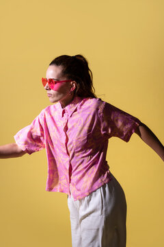 Young woman dancer posing in studio on yellow background
