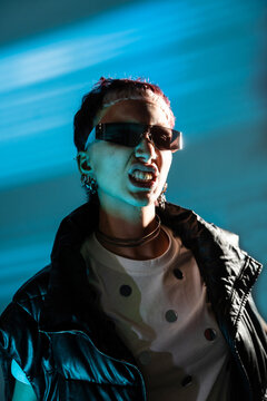 Cyberpunk woman in neon light with sunglasses and jacket