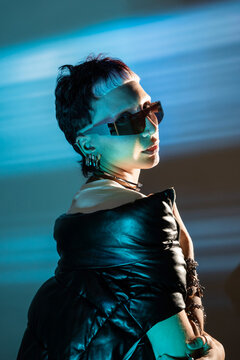 Cyberpunk woman in neon light wearing visor and leather