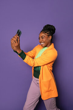 Young afro woman taking a selfie with smartphone in studio