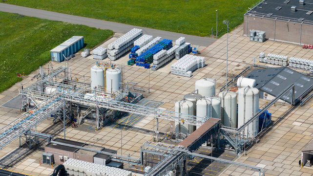 Aerial view of the Seqora B.V. industrial facility featuring large storage tanks, complex piping systems, and rows of storage containers on a paved yard in Zaltbommel, Gelderland, Netherlands.