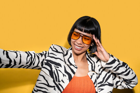 Smiling latin young woman in zebra jacket on yellow