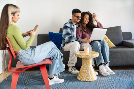 Multiethnic flatmates relaxing together with laptop at home