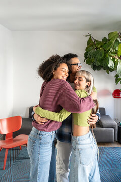 Multiethnic flatmates hugging together in living room