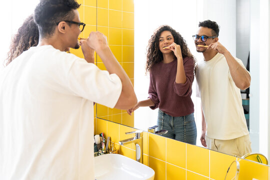 Latin couple brushing teeth together in modern bathroom