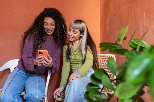 Multiethnic flatmates sharing a smartphone at home