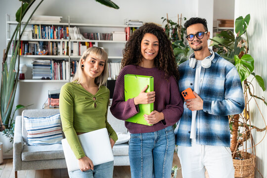 Multiethnic flatmates with laptop and folders at home