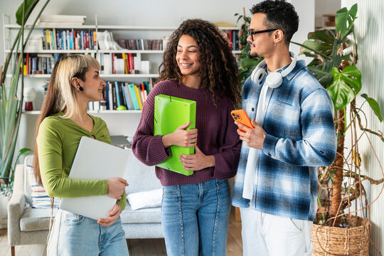 Multiethnic flatmates chatting at home with folders