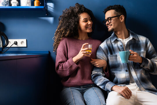 Latin couple sharing coffee and smiling in cozy kitchen