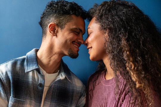 Latin couple sharing an intimate moment against blue wall
