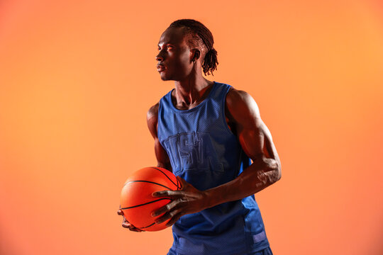 Black basket man holding ball in studio orange background