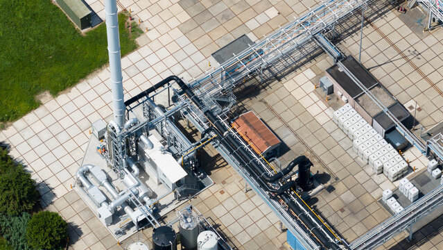 Aerial view of Seqora B.V. industrial facility featuring a tall white chimney, complex network of pipes, storage tanks, and paved grounds in Zaltbommel, Gelderland, Netherlands.
