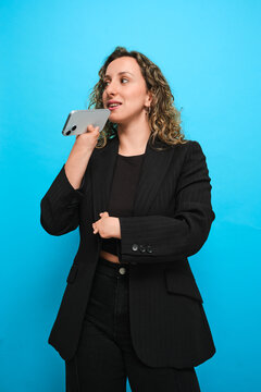 Woman using smartphone voice message on blue studio background