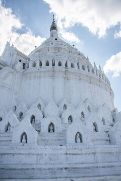 White Buddhist stupa in Myanmar against cloudy sky