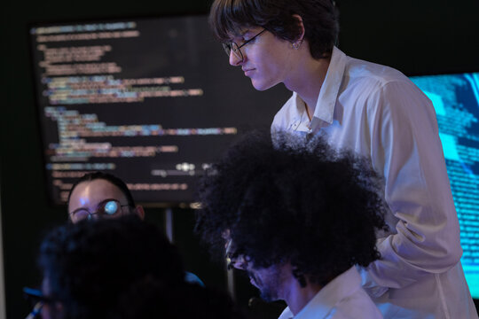 Low-light scene where an Asian woman developer extends a hand toward the display in a modern technology office bathed in blue light, capturing collaboration on an inclusive (frame 447)