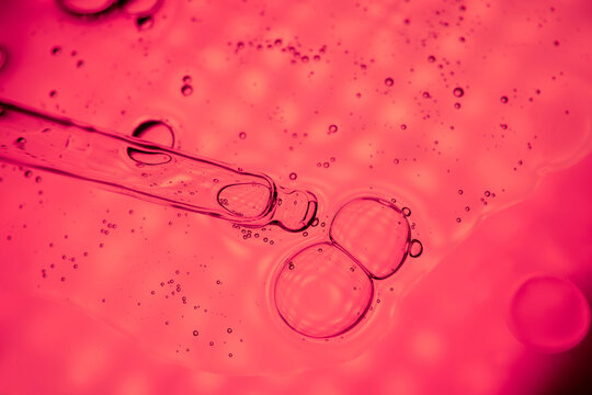 Pink serum bubbles with glass dropper in macro abstract