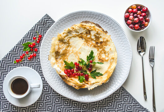 Minimal breakfast crepe with berry garnish and coffee