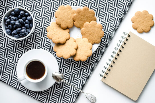 Cozy coffee break with cookies, blueberry bowl and notebook