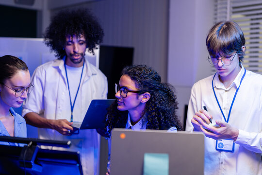 Cinematic shot of a diverse, multiethnic software team focu together at the workstations in a modern technology office bathed in blue light, a portrait of inclusion and (frame 997)