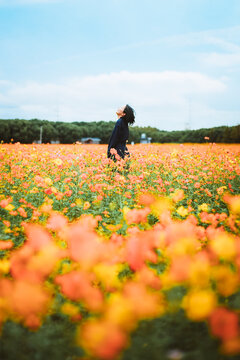 Side view of a beautiful Asian woman looking back and smiling in the yellow flower field at Sunhu Flower Sea in Ningbo, Zhejiang, China