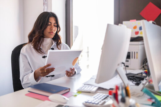 Woman reviewing paperwork at desk in modern office