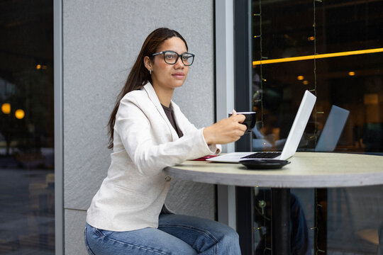 Woman enjoying coffee break while working on laptop