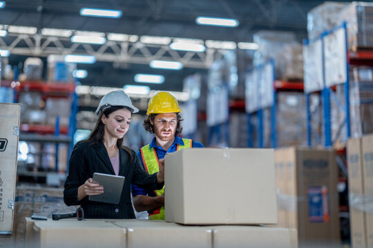 Diverse team of warehouse managers and workers inspecting a cardboard box in a modern logistics distribution center
