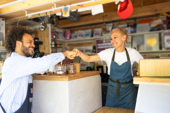 Two employees at coffee kiosk share a friendly fist bump