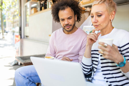 Takeaway coffee at a kiosk with coworkers using laptop