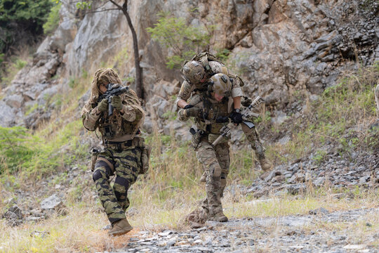 Soldier carries injured comrade over rocky terrain