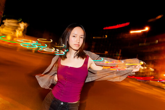 Asian woman posing at night with motion blur city lights