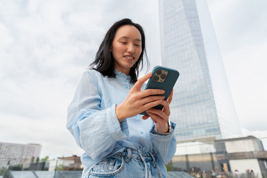Gen Z Asian woman using smartphone in modern city
