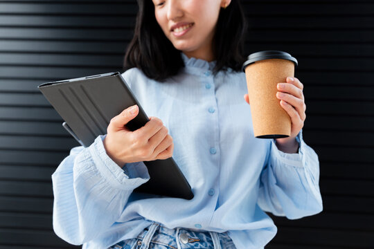 Gen Z Asian woman using tablet with coffee on break