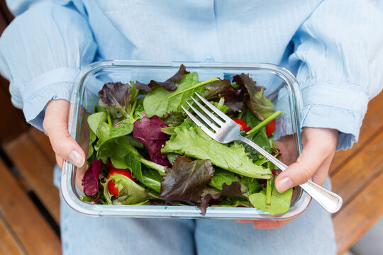 Healthy mixed salad in glass lunch box held in hands