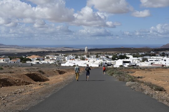 Tourists on a street near Teguise, view of town, white houses of Teguise with church tower, Lanzarote, Canary Islands, Spain