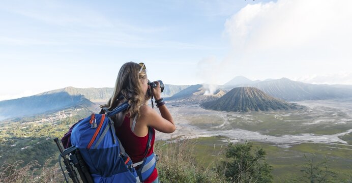 Tourist with camera, smoking volcano Gunung Bromo, Mt. Batok at front, Mt. Kursi at back, Mt. Gunung Semeru, Bromo Tengger Semeru National Park, Java, Indonesia