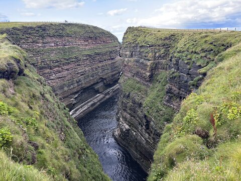 Deep gorge between steep cliffs with green grass covers, Duncansby Stacks, John O' Groats Scotland, United Kingdom