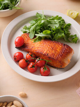 Pan-seared salmon filet served with cherry tomatoes and arugula