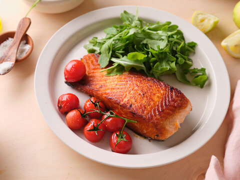 Pan-seared salmon filet served with cherry tomatoes and arugula