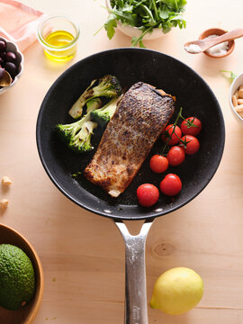 Pan-seared salmon filet with broccoli and cherry tomatoes in a skillet